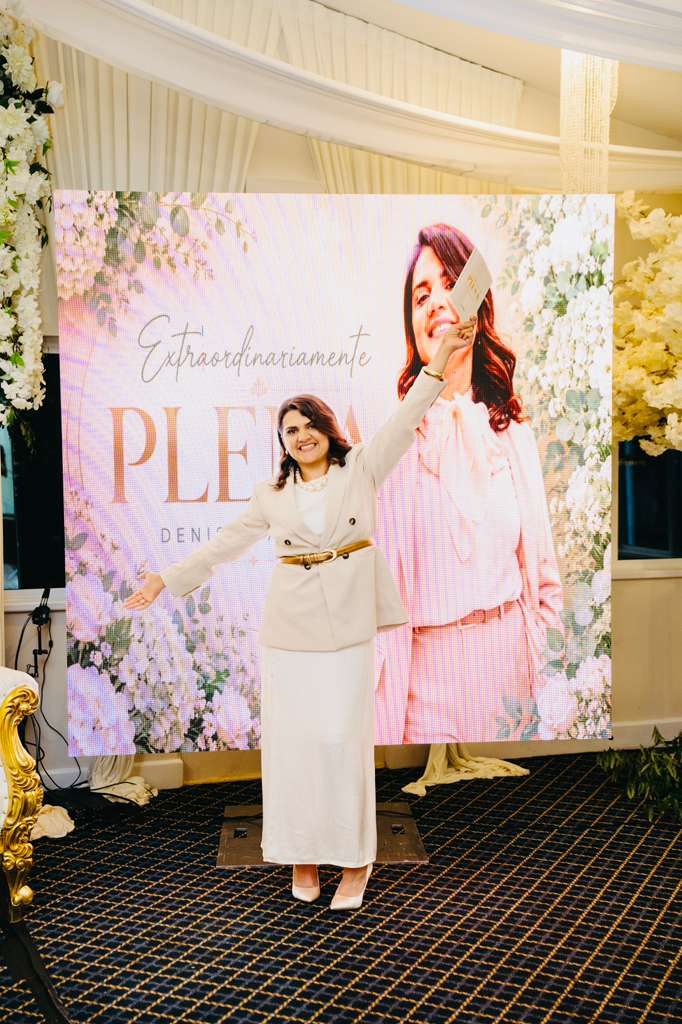 Denise Sampaio em frente ao painel do livro Extraordinariamente Plena